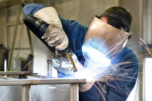Professional stainless steel welding process with sparks in industrial fabrication workshop